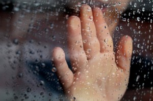 hand on rainy glass window